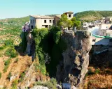 Casas aferradas a un acantilado, con vegetación cubriendo la roca. El mirador de la Molatica ofrece vistas espectaculares del paisaje.