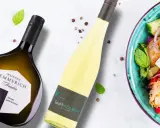 Zwei Flaschen Wein, eine davon eine Scheurebe aus Franken, neben einem bunten Salat.