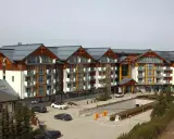 Widok z kamer w Bukowinie Tatrzańskiej na nowoczesny hotel z drewnianymi elementami i parkingiem.