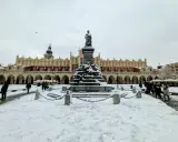 Zimowy weekend w Krakowie. Rynek Główny ze Sukiennicami i pomnikiem Adama Mickiewicza, pokryty śniegiem.