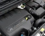 Silnik 2.0 HDI pod czarną osłoną z logo Peugeot. Widać przewody, filtr powietrza i zbiorniczek płynu.