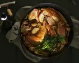 Ein Brathähnchen mit Zwiebeln und Kräutern, bereit zum Genuss. Dazu ein Glas Wein, der den Riesling Geschmack unterstreicht.