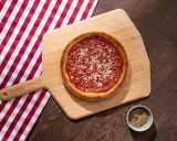 Pizza sur planche en bois, avec une nappe à carreaux rouges et blancs. La proportion levain farine eau est parfaite pour cette croûte dorée.