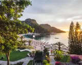 Malownicza zatoka z łodziami, plaża z leżakami i palmami, a na zboczu wzgórza wspaniały hillside beach club.