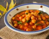 Un savoureux curry de pois chiche, aux couleurs chaudes, servi dans un bol décoré. Une touche de verdure et des feuilles jaunes apportent une note automnale.