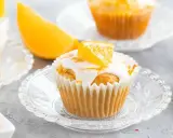 Fanta Muffins mit weißer Glasur und Orangenspalten, serviert auf kleinen Glastellern.