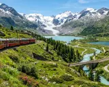 Il trenino del Bernina percorre un paesaggio alpino mozzafiato, con laghi turchesi, montagne innevate e verdi pendii fioriti.