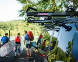 Ludzie przygotowują się do wodnej przygody, transport kajaka i desek SUP do jeziora.