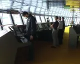 Equipaggio sulla plancia nave da crociera, con strumenti di navigazione e grandi finestre.