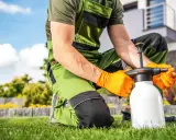 Jardinero con guantes naranjas prepara un pulverizador, buscando alternativas al glifosato para un cuidado ecológico del césped.