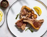 Côtelettes d'agneau grillées, parfumées à la marinade, garnies de romarin frais et de quartiers de citron.