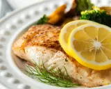 Pieczony halibut z cytryną i koperkiem, podany z pieczonymi ziemniakami i brokułami. Zdrowe danie, które nie musi mieć wielu halibut kcal.