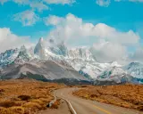 Droga wije się przez trawiastą równinę w kierunku majestatycznych, ośnieżonych szczytów Patagonii. Idealne miejsce dla marki Patagonia.