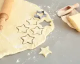 Plätzchenteig zu krümelig? Sterne werden ausgestochen. Teig, Nudelholz, Butter und Mehl sind bereit für leckere Kekse.