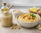 Pyszny hummus z ciecierzycą, czosnkiem i oliwą. Słoik z kremowym tahini, które jest kluczowym składnikiem.