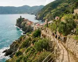 Sentiero panoramico tra i vigneti delle Cinque Terre, con vista sul mare blu e sui colorati borghi aggrappati alla scogliera.