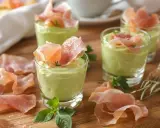 Petits verrines de mousse de chevre onctueuse, garnies de fines tranches de jambon cru et de quelques herbes fraîches.