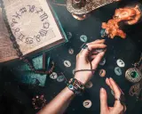 Ręce trzymają kamienie z runami, obok księga z symbolami zodiaku. To wszystko sugeruje, że godzina urodzenia numerologia może być kluczem do odczytania przyszłości.