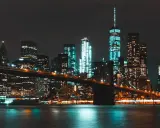 Il Ponte di Brooklyn illumina la **new york city vita notturna**, con grattacieli scintillanti che si riflettono sull'acqua scura.