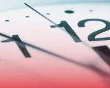 Zbliżenie na tarczę zegara z cyframi 11 i 12. Czas biegnie, ile godzin pracy w miesiącu?