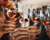 Hände halten Gläser mit Roséwein. Ein Genuss ohne Sulfite, vegan und köstlich.