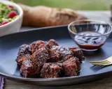 Saftige, karamellisierte **burnt ends** auf einem Teller mit BBQ-Sauce und Salat. Ein Fest für Fleischliebhaber!