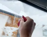 Dłoń zeskrobuje szron na szybie, odsłaniając fragmenty drewnianej elewacji. Zima daje się we znaki.