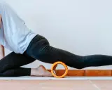 Frau in Sportkleidung dehnt sich mit einem Faszienroller.