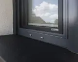 Szary parapet zewnętrzny pod oknem z moskitierą. Zastanawiasz się, czym przykleić parapet zewnętrzny blaszany?