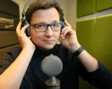 Mężczyzna w słuchawkach i okularach, gotowy do nagrania. Może to lektor porno, a może czyta bajki.