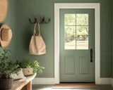 Un recibidor pintado en verde musgo, con sombreros de paja, plantas y un bolso. Inspírate para saber como pintar una habitacion.