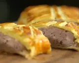 Tranche d'un plat lorrain, une viande savoureuse enveloppée dans une pâte feuilletée dorée.