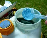 Préparation du traitement choux bouillie bordelaise. Une cuillère bleue de poudre est versée dans un pulvérisateur.