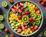 Un bol coloré de salade de fruits printemps : fraises, kiwis, ananas, myrtilles et mûres. Parfait pour un repas léger et rafraîchissant.