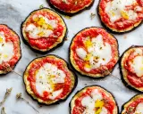 Pizzette di melanzane pronte per essere gustate, con pomodoro, mozzarella filante e un filo d'olio.
