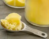 Łyżka z masłem klarowanym, obok słoika. Czy masło klarowane jest zdrowe? To tłuszcz ceniony w kuchni ajurwedyjskiej.