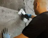 Mann verputzt Wand mit Armierungsgewebe. Perfekt für den Ausbau des Kellers.