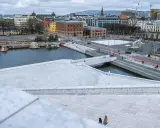 Widok z punktu widokowego Oslo na nowoczesną architekturę, wodę i plac z rzeźbą.