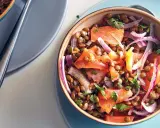 Salade de lentilles savoureuse avec des morceaux de saumon, des oignons rouges et du persil frais. Un plat coloré et nutritif.