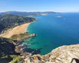 Blick vom Berg auf eine Bucht mit Sandstrand und türkisfarbenem Meer. Perfekt für eine Wanderung im Baskenland.