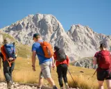 Escursionisti si dirigono verso un imponente corno grande, con zaini colorati e bastoncini da trekking.