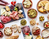 Un festin de tapas pour une pendaison de crémaillère : charcuterie, fromages, olives, cornichons, fruits secs et pain.
