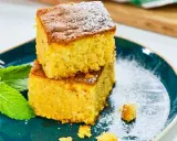 Dos porciones de bizcocho de calabaza espolvoreadas con azúcar glas, acompañadas de hojas de menta fresca en un plato azul.
