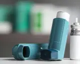 Zwei Inhalatoren, einer davon ein Symbicort-Spray, liegen auf einer weißen Oberfläche.