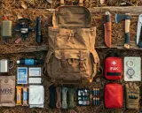 Preppers kto to? Zestaw survivalowy: plecak, nóż, siekiera, latarka, apteczka, mapa, kompas, racje żywnościowe, termos, filtr do wody, baterie.