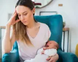 Zmęczona mama z płaczącym niemowlakiem na rękach, w fotelu, w poszukiwaniu siebie.