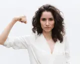 Kobieta pokazuje biceps, symbolizując siłę. Może to być metafora objawów wysokiego testosteronu, takich jak pewność siebie i determinacja.