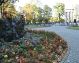 Jesienny park strzelecki Tarnów. Kolorowe rabaty kwiatowe i liście na brukowanej ścieżce.
