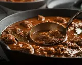 Un ricco spezzatino, uno dei piatti tipici del Friuli Venezia Giulia, servito in una padella di ghisa con un mestolo.