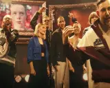 Witajcie w naszej bajce! Kto śpiewa? Grupa ludzi na scenie, z portretem w tle, w radosnym nastroju.